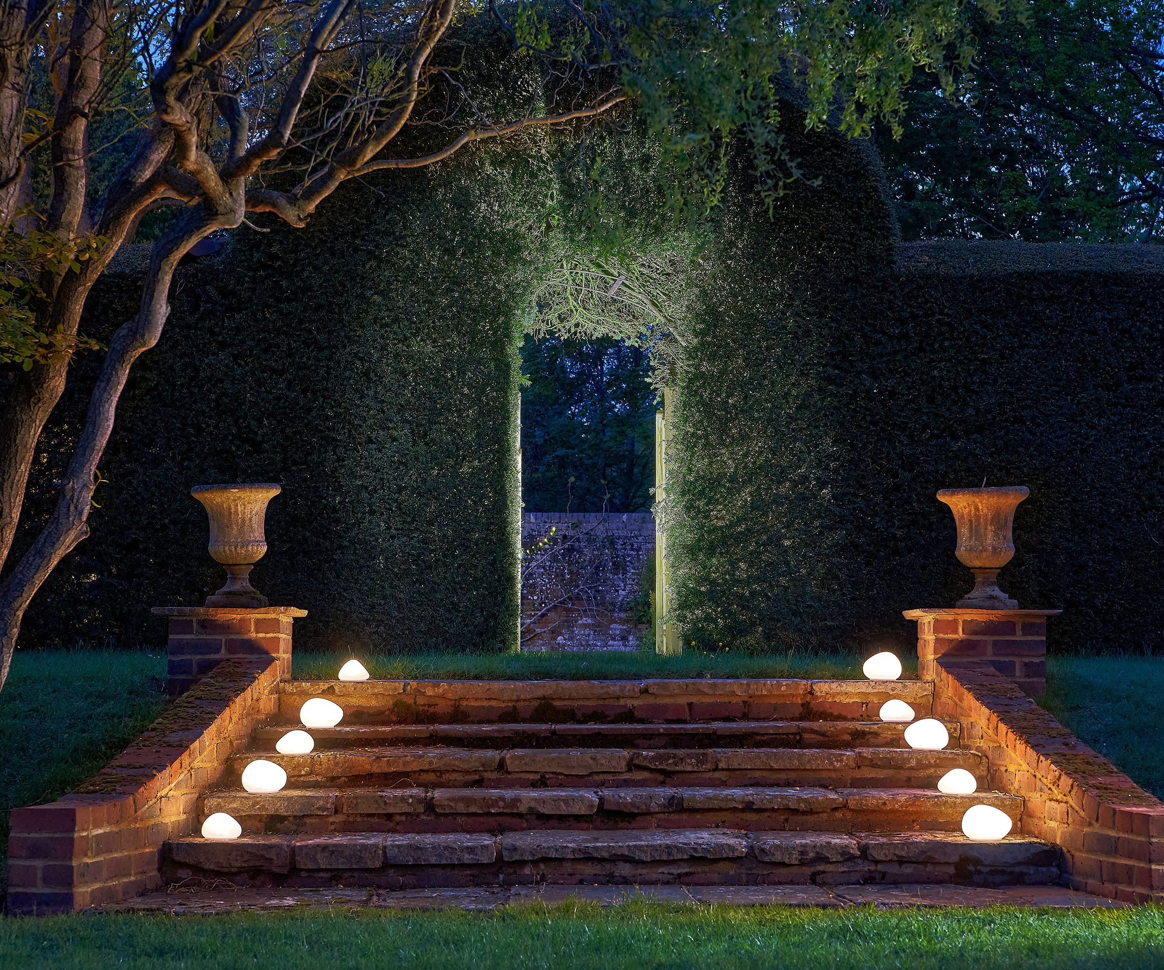 Solar Powered Glass Pebble lining some stone steps in a garden