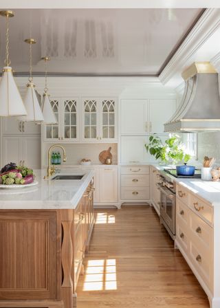 A kitchen with white cabinets, wooden flooring, and a large island