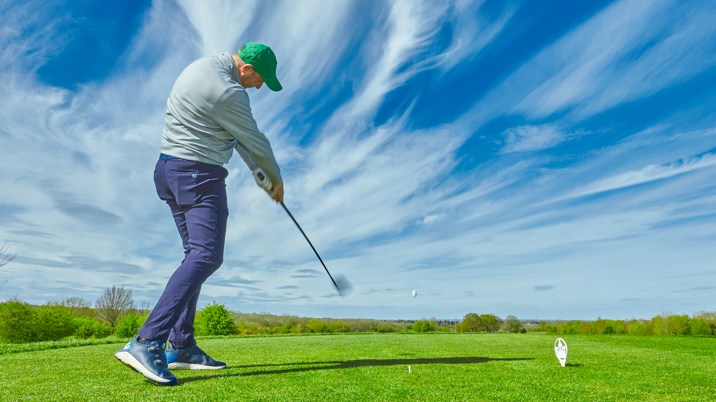 A golfer just after impact on a drive from behind