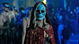 Carla Gugino's Verna stands in a nightclub with a skull mask on in The Fall of the House of Usher