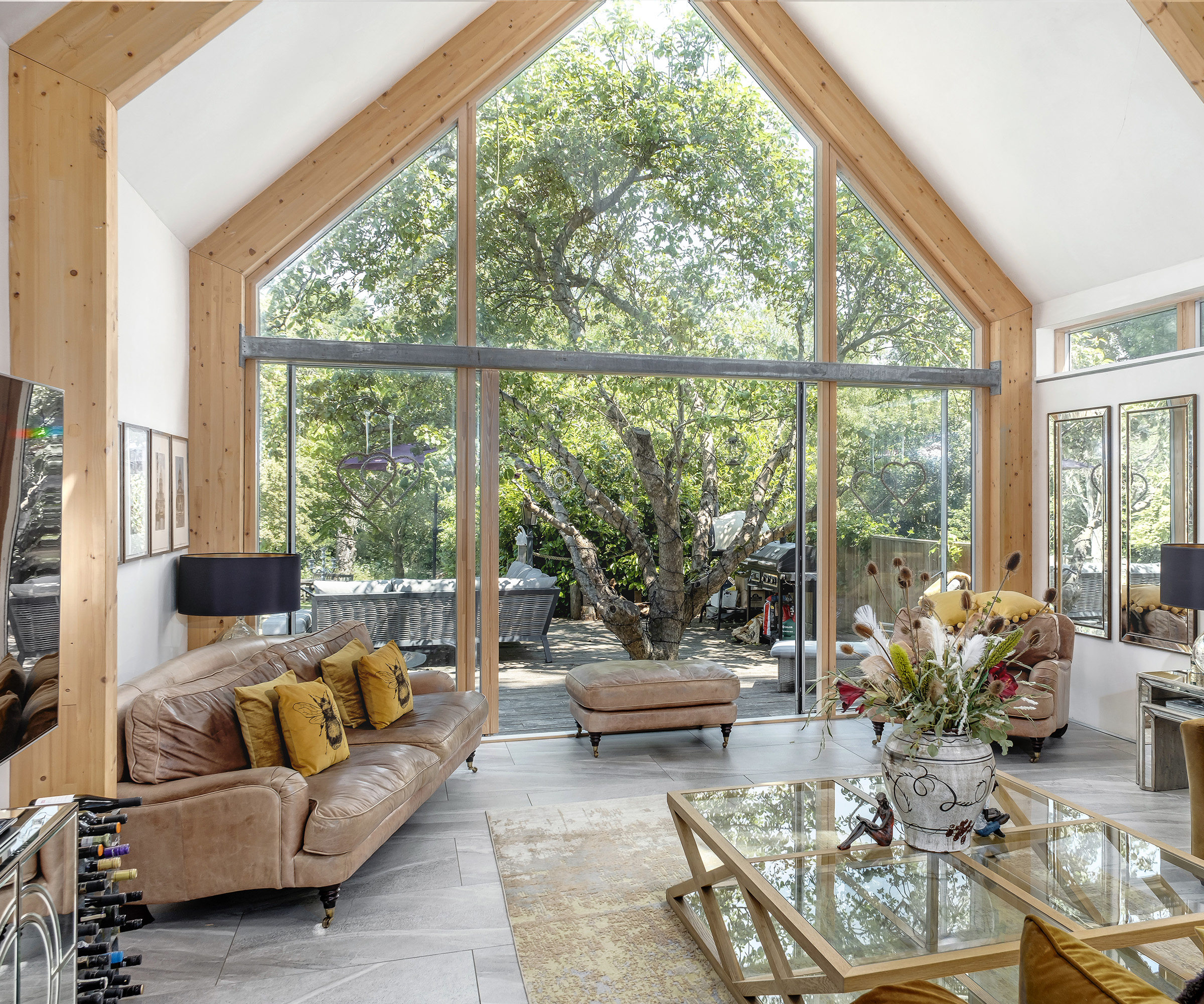 An open plan living room with large architectural glazing with sliding glass doors.