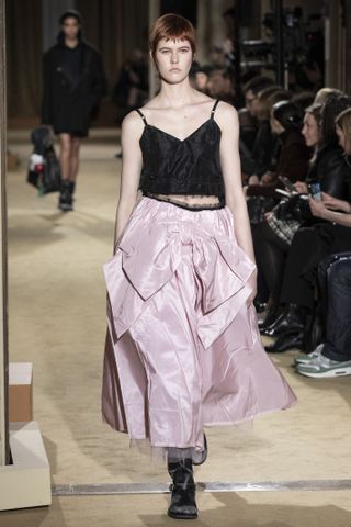 A model walks the runway at the coach fall 2024 show wearing a bow skirt and a black tank top