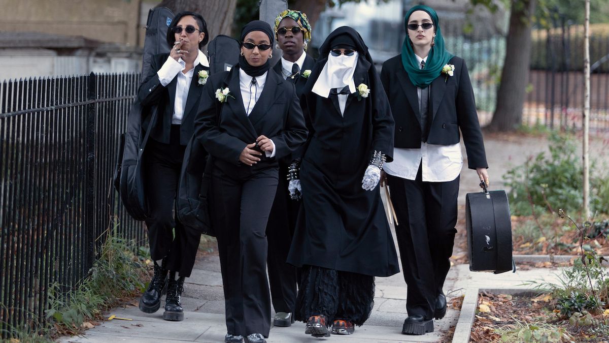 We Are Lady Parts band in matching suits heading to a wedding in Season 2