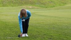 A golfer measuring two club-lengths