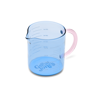 A blue tinted glass measuring cup with light pink handle