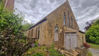 A chapel with wooden doors and a small garden