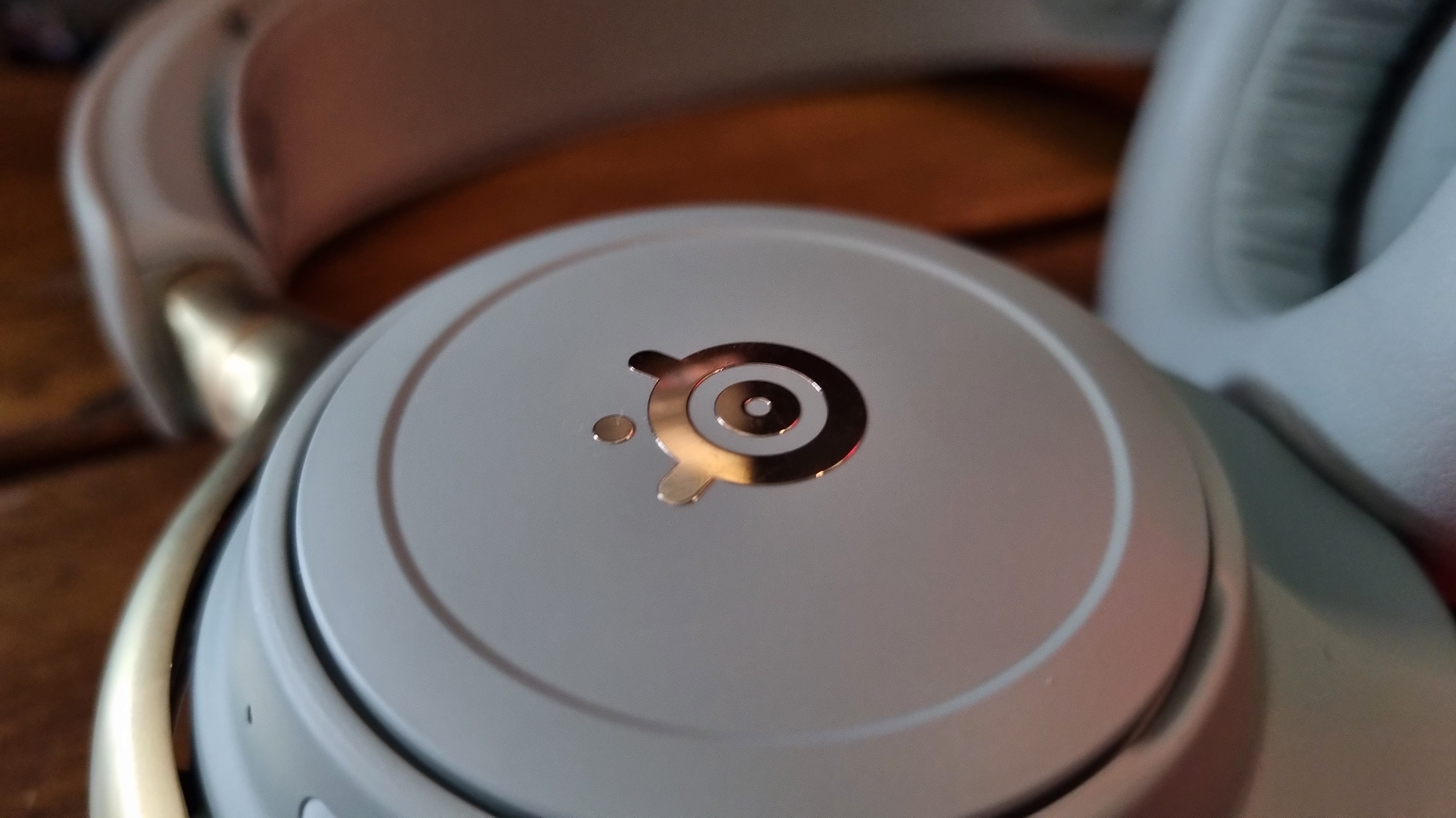 A gold SteelSeries logo on the side of the SteelSeries Arctis Nova Elite gaming headset