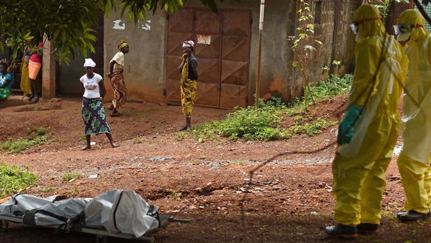 Health workers from in Sierra Leone&amp;#039;s stand near a corpse 