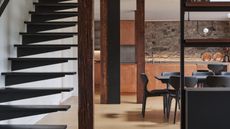 A kitchen with a staircase. The kitchen has lots of dark features that match the staircase!