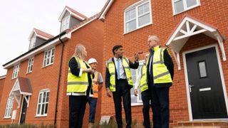 Rishi Sunak and Michael Gove standing outside the front of some newly built brick houses