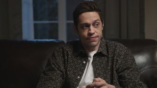 Pete Davidson sitting on a couch in Bupkis