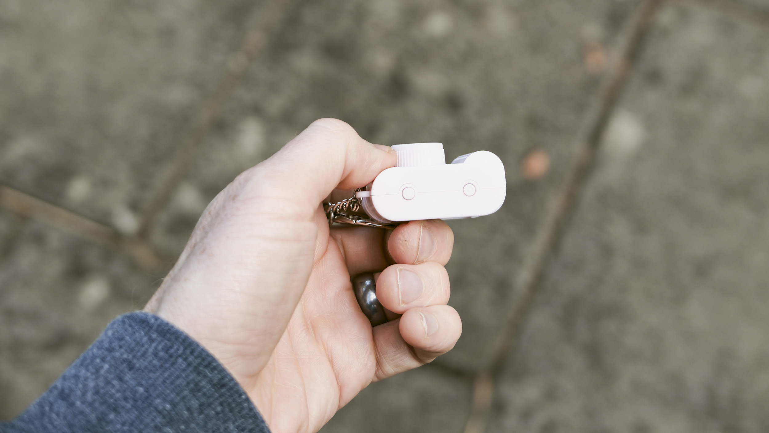 Miniature pink keychain camera, the 'Photo Creator Mini Digital Camera series 3', in user's hand, its topside