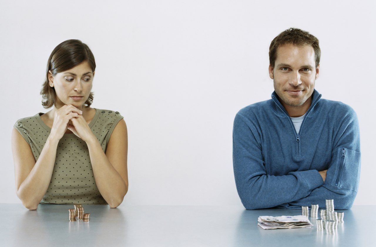 Man and Woman Sit Next to each Other With a Pile of Money in Front of Them, Woman Looking Jealous at Man&amp;#039;s Pile