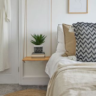 bedroom with white wall and bedside table with plant pot