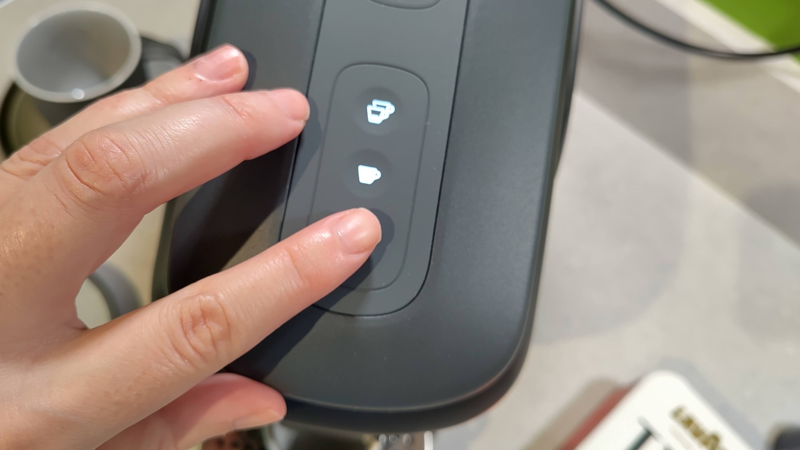 Hand pressing button on top of Lavazza Tabli coffee maker