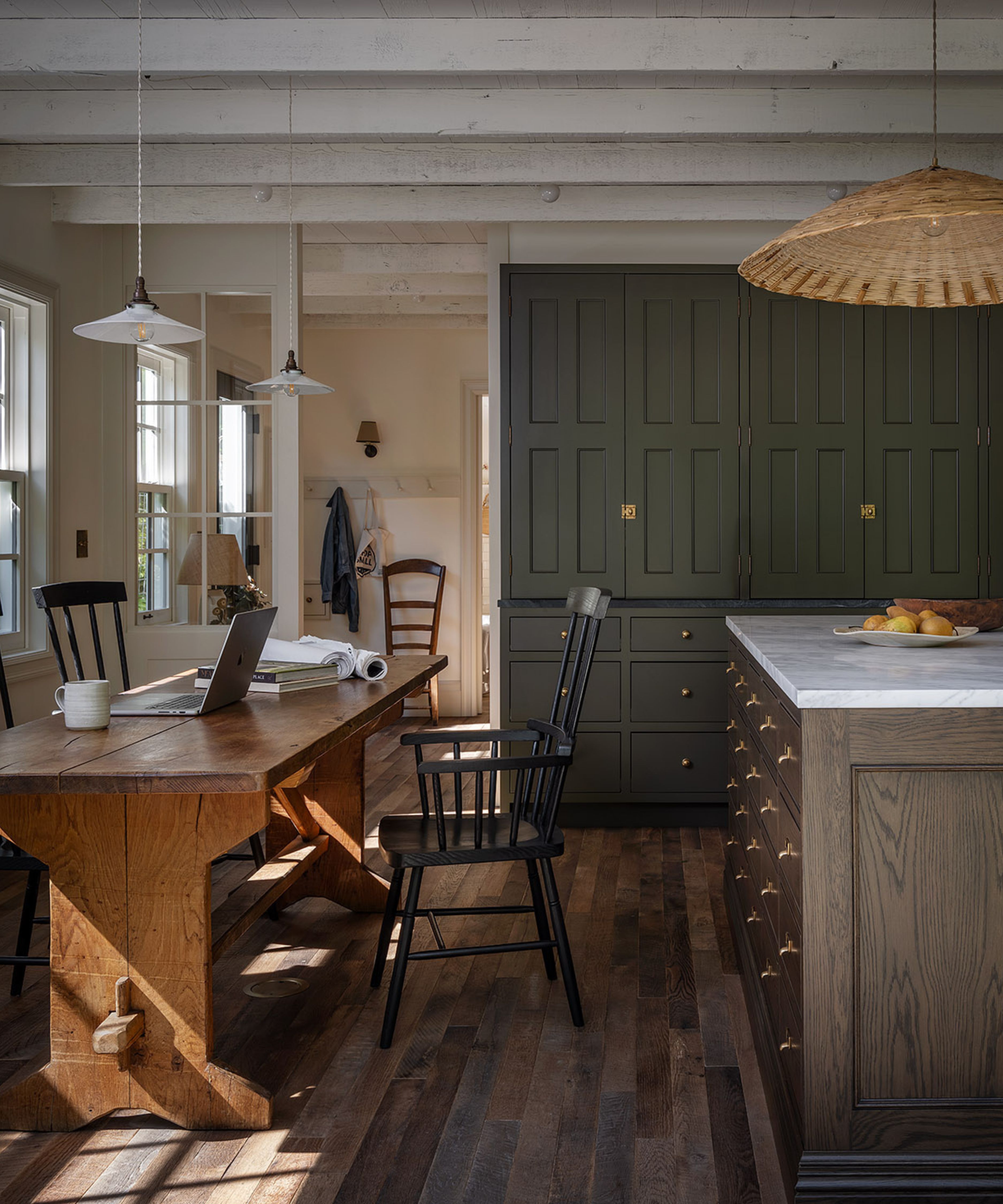 a converted garage ADU with rustic beams and an olive green kitchen with large dark wooden island and a rustic farmhouse table