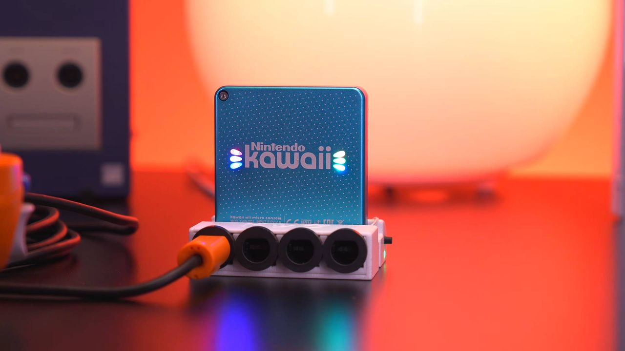 Close up of Nintendo Kawaii connected to white dock with orange GameCube controller connected.
