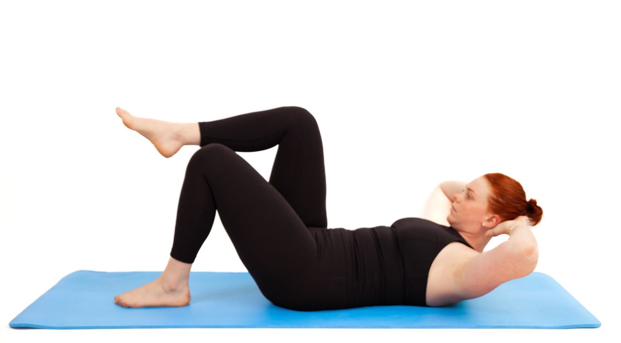 Woman demonstrates Pilates exercise on blue exercise mat against white background