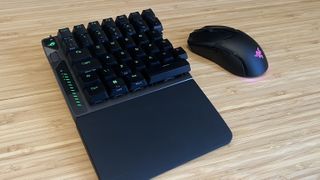 Half of the Asus ROG Falcata gaming keyboard on a wooden desk with a gaming mouse next to it
