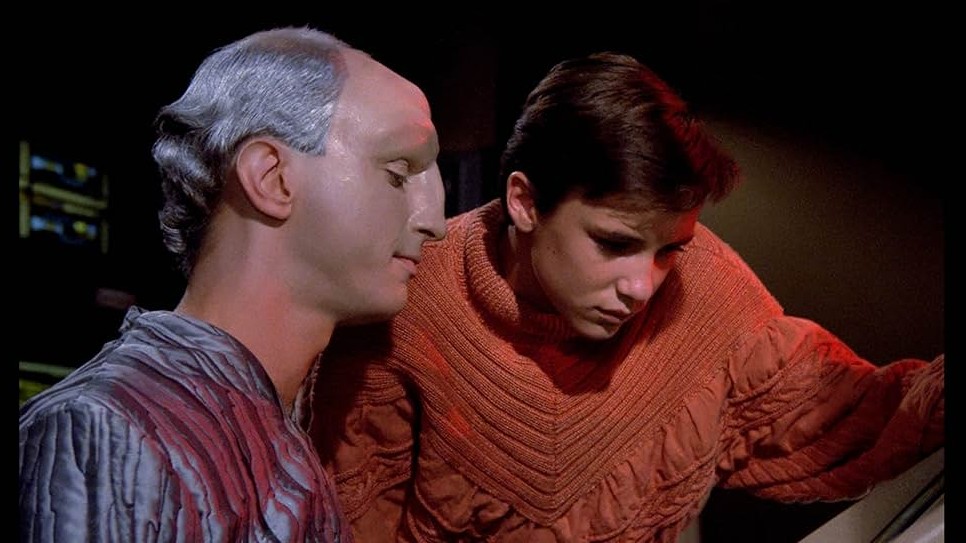 The Traveler, an extraordinary being, takes an interest in the boy genius, Wesley Crusher (who is wearing some fabulous orange knitwear).