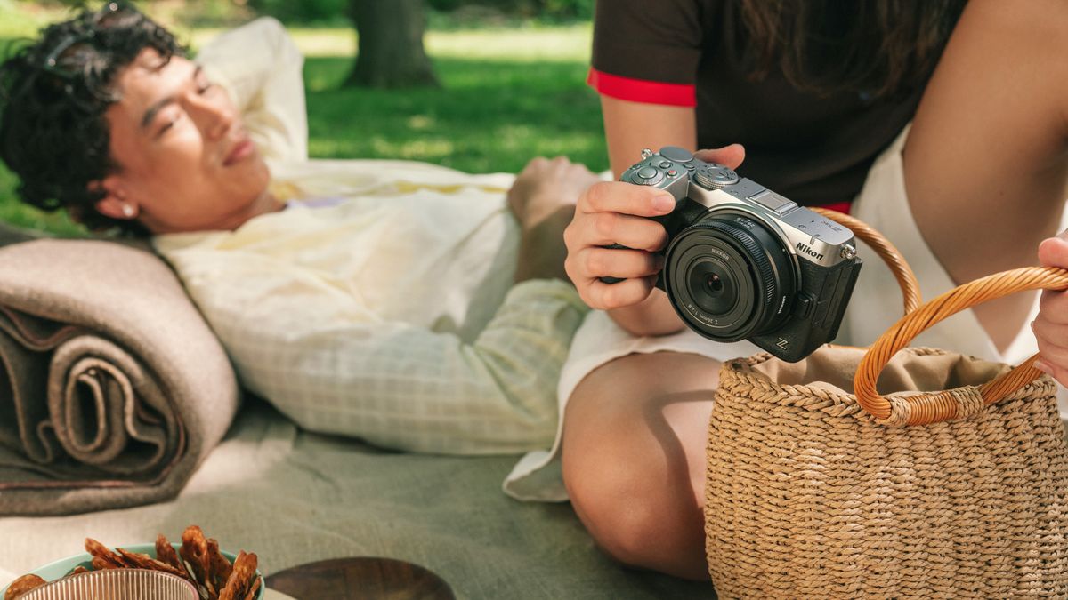 Person taking the Nikon Z5 II C mirrorless camera out of their bag, they're having a park picnic