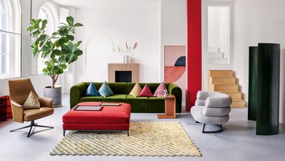 Formal sitting room with olive green sofa, red squar eottoman, tan armchair, blue and gold rug and pink accents