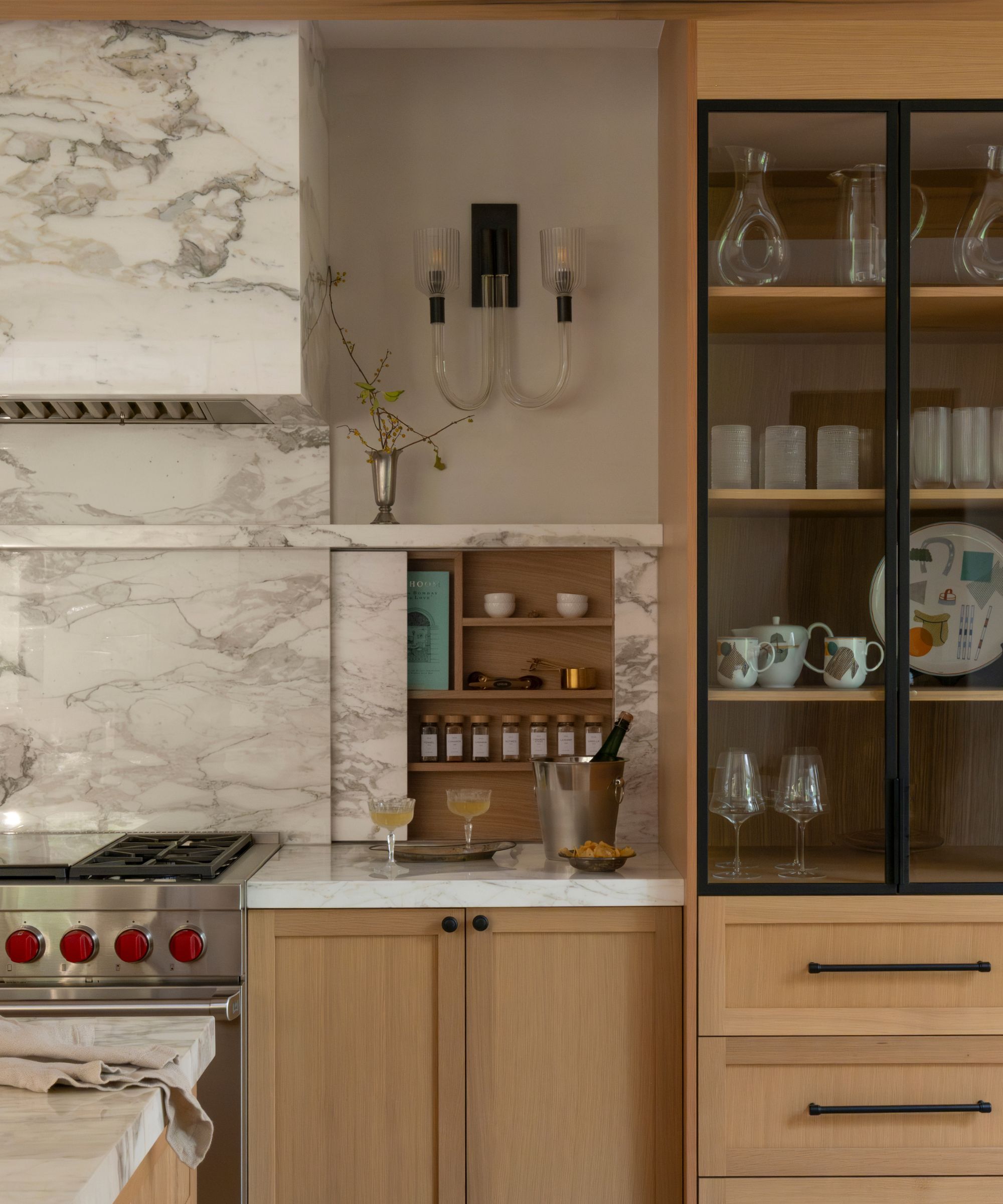 A kitchen with wood cabinets, marble countertops, and a marble backsplash with hidden storage