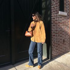 Anna wears a suede jacket, blue jeans, and suede sneakers.