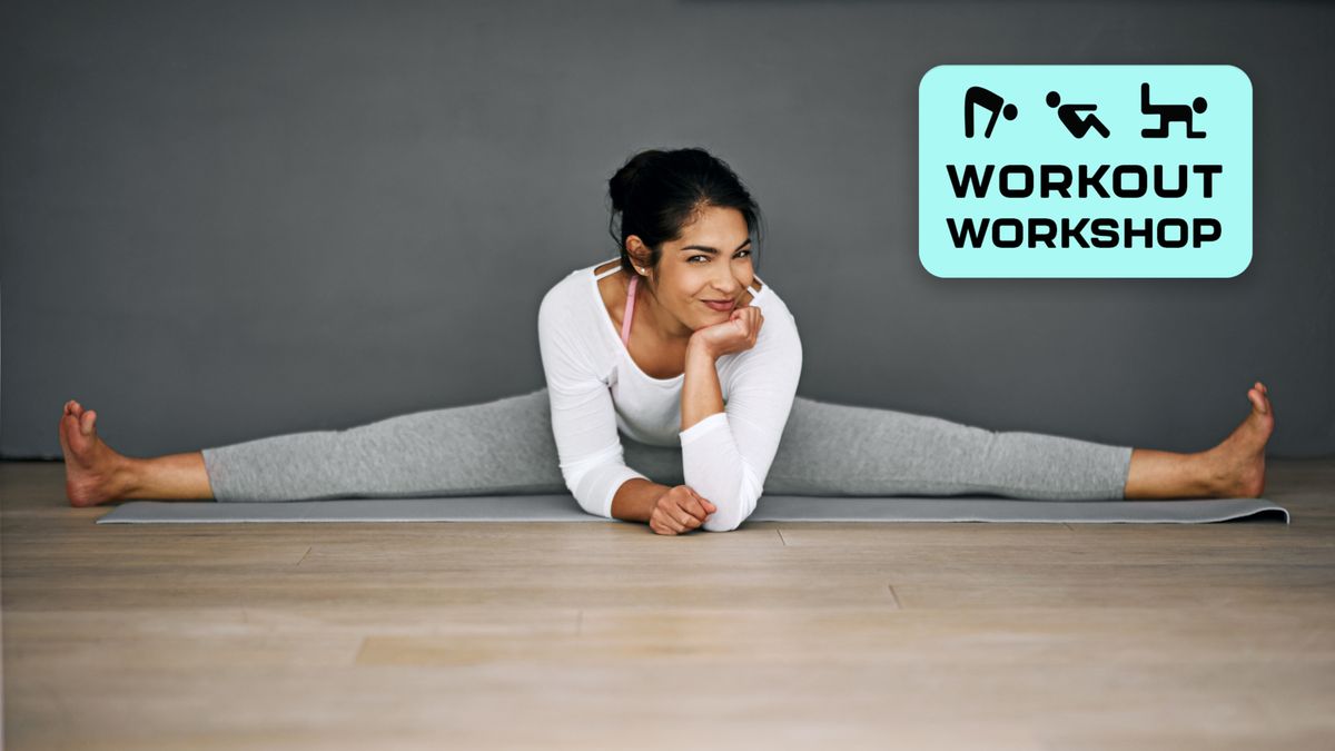 Woman in studio on exercise mat performing the splits while leaning on elbows and smiling at camera