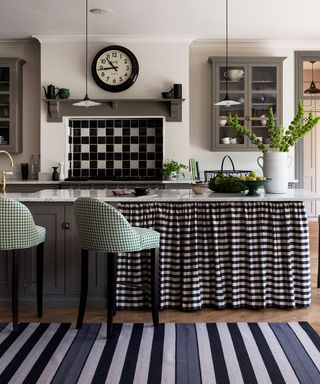 Kitchen pictures showing a monochrome kitchen with gingham drapes under the cabinetry and gingham bar stools.