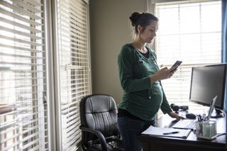pregnant woman standing in her home office