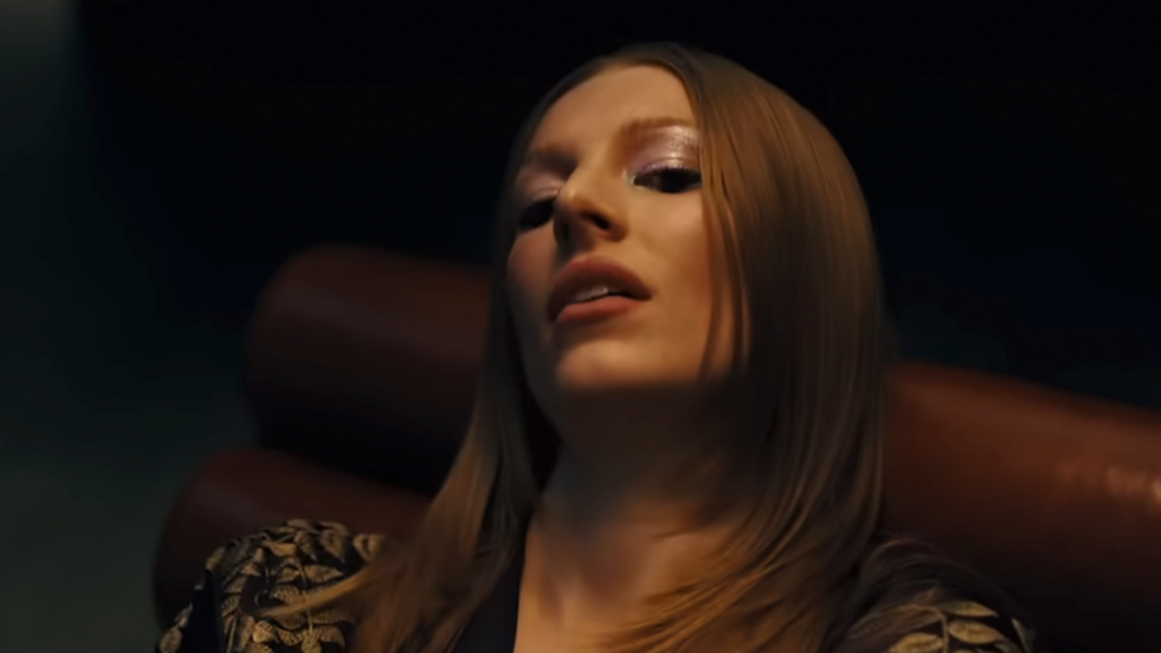 Hunter Schafer with her head back on a chair, looking down in Euphoria.