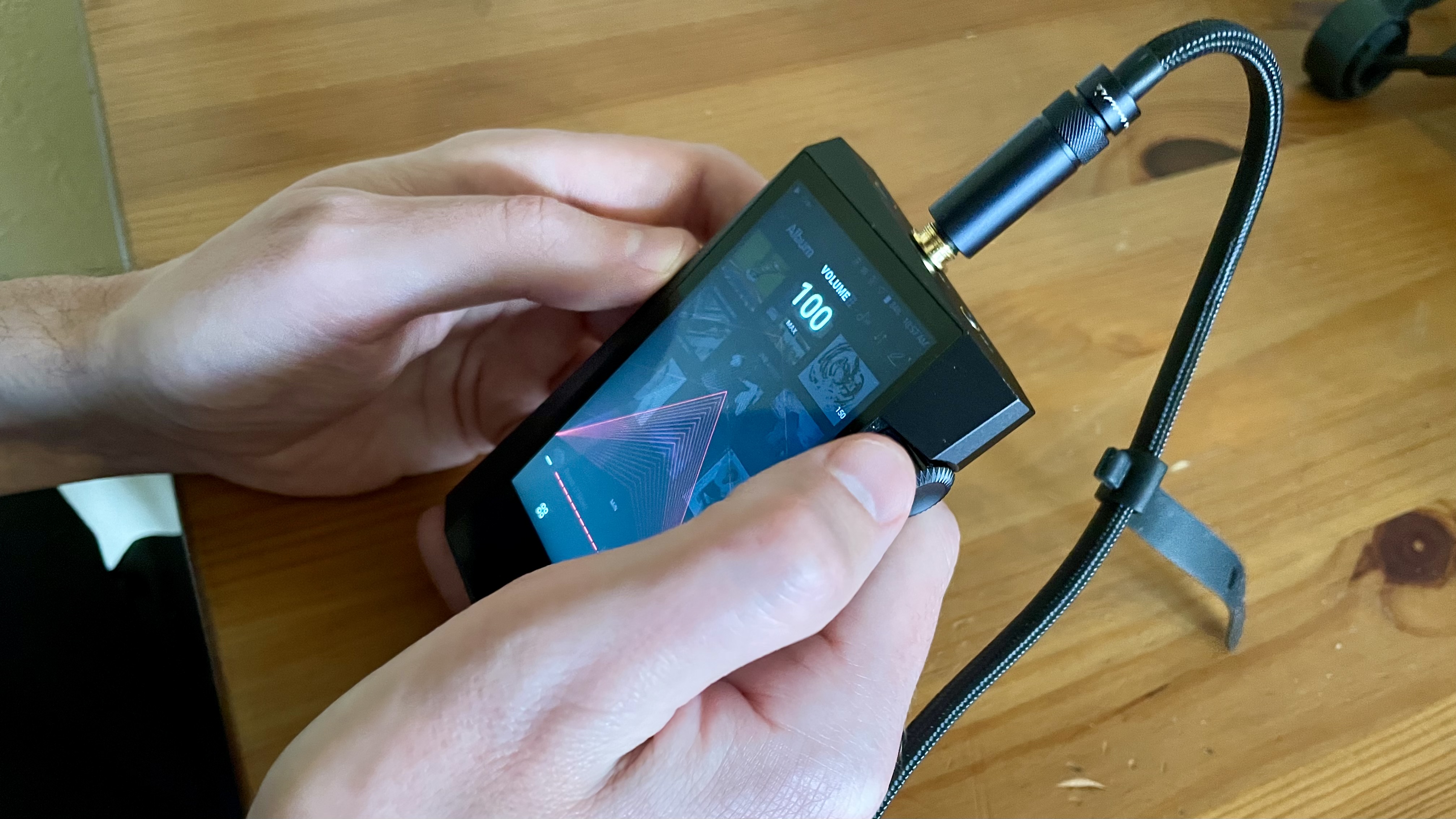 Astell & Kern A&norma SR35 held in a hand, scrolling the volume up to 120