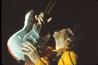 Jimi Hendrix onstage holding his guitar aloft