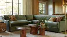 a green couch, three marble tables, a floor lamp, and pillows on the couch