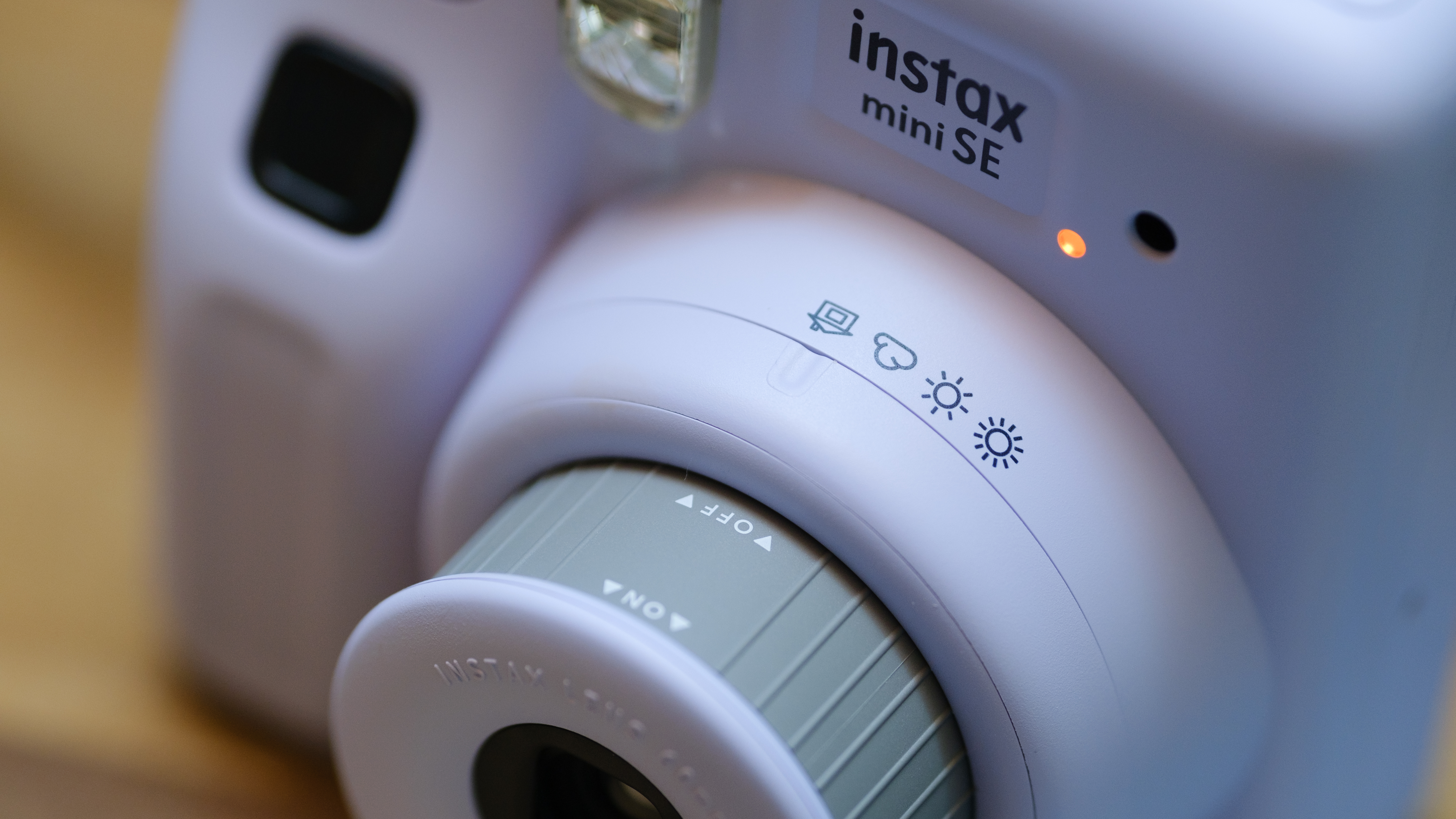 A close-up of the Instax Mini SE lens with brightness control