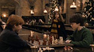 Hermione approaching Harry and Ron. as they play Wizard Chess in the great hall.