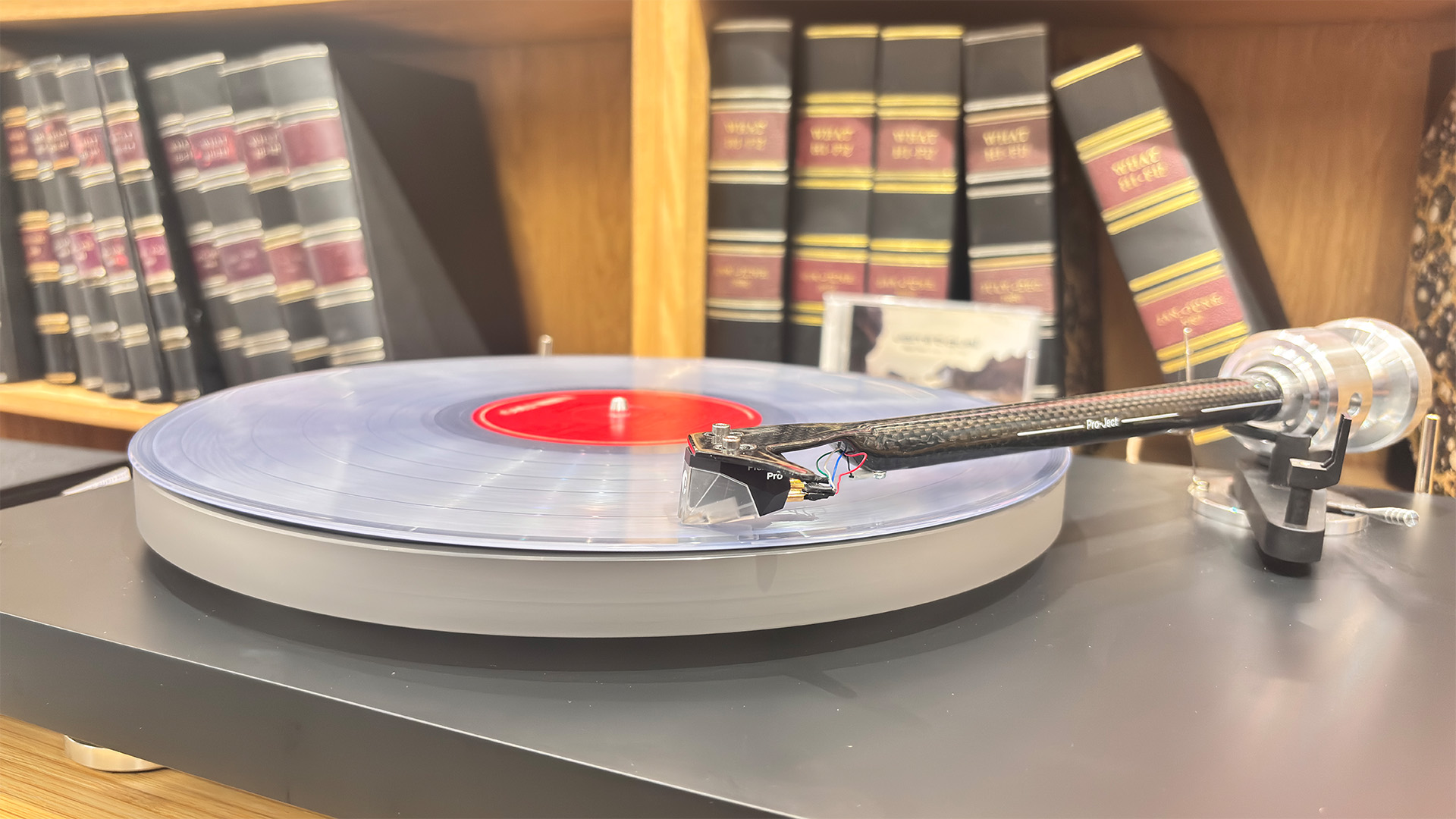 Pro-Ject Debut Reference 10 turntable in front of bookcase playing clear vinyl record