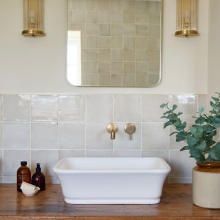 bathroom sink area with mirror, bass and reeded glass wall lights, white basin and brushed brass basin mixer