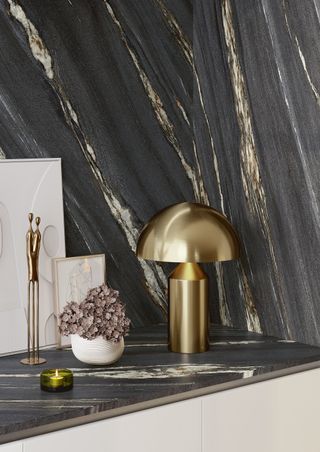 A black marble kitchen countertop and backsplash, with a gold lamp in the corner