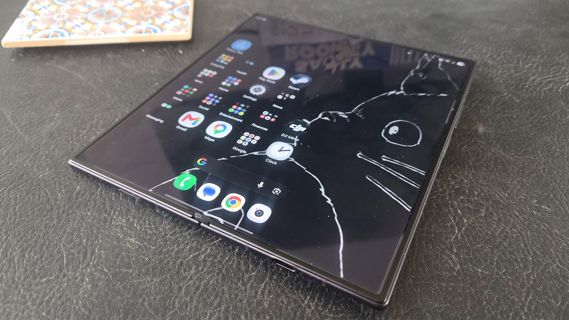 Samsung Z Fold 8 Ultra smartphone on grey surface, on screen are apps and line drawing of cat