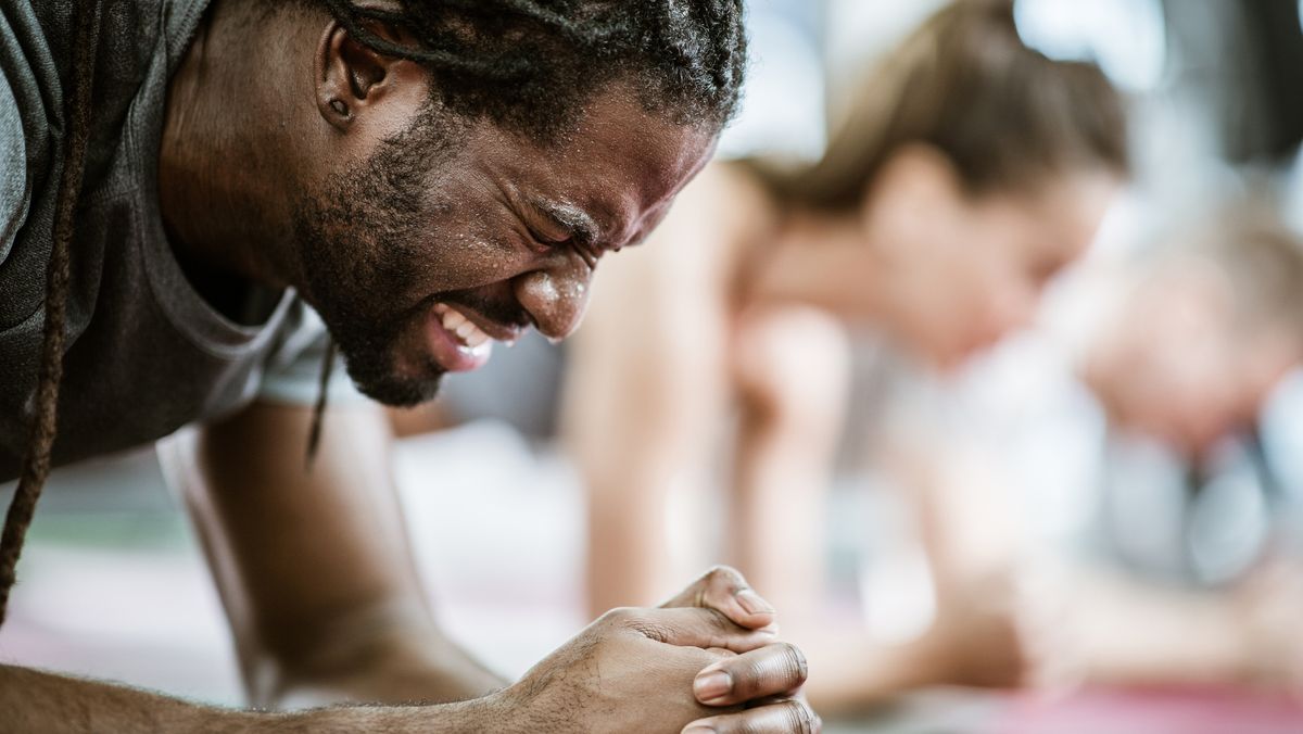 Man grimaces as he holds plank position