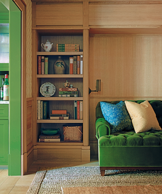 Corner of living area in elegant boston house with velvet green sofa and book shelves