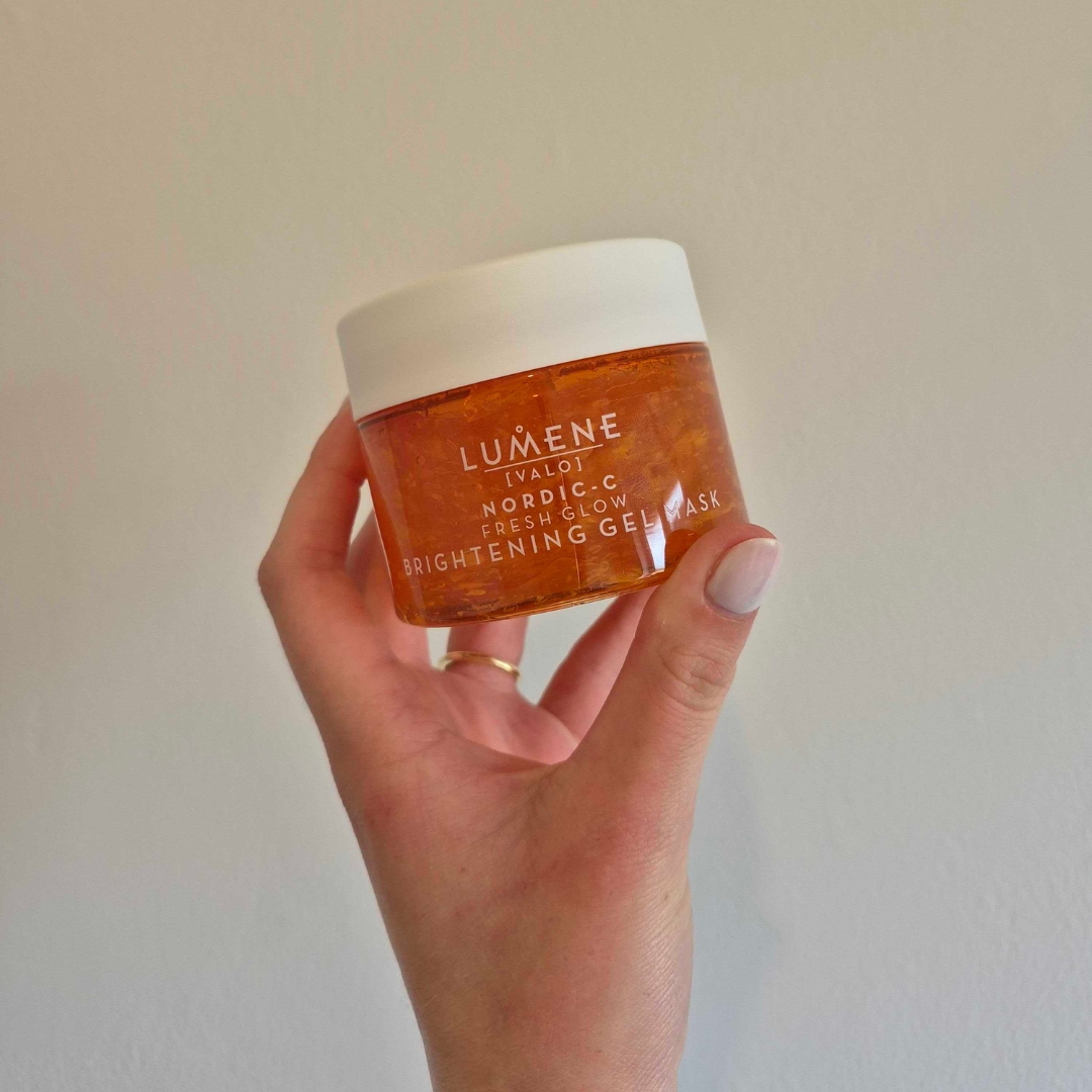 A close-up of Digital Beauty Writer, Naomi Jamieson holding up the Lumene Fresh Glow Brightening Gel Mask, in front of a cream wall