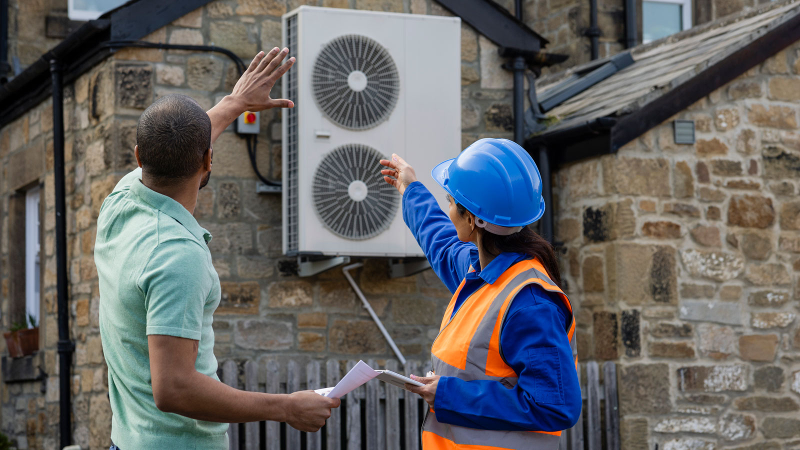 man and woman with hard hat looking at HVAC system