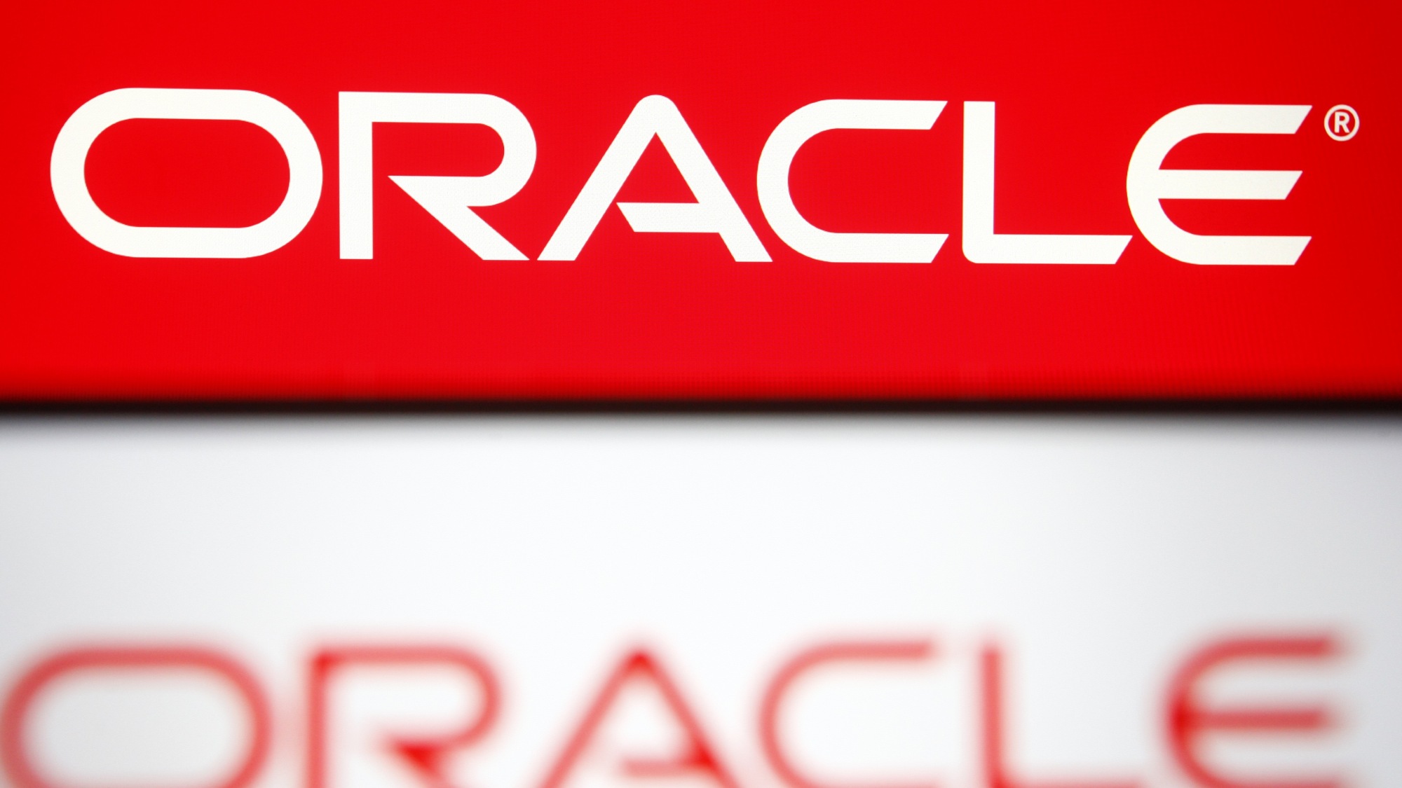 An Oracle logo of a US multinational computer technology corporation is seen on a smartphone and a pc screen.