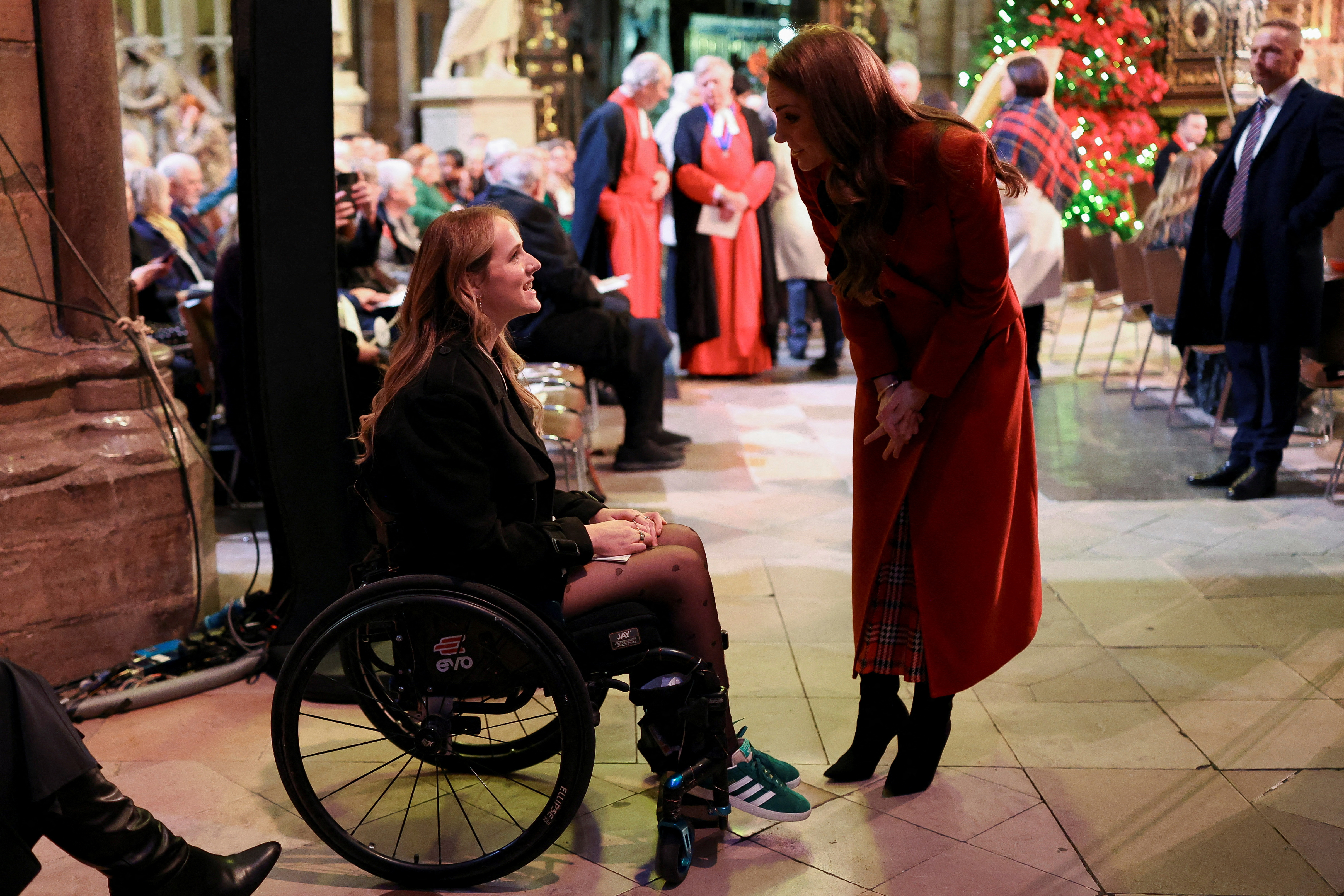 Kate Middleton bending over and talking to a woman in a wheelchair