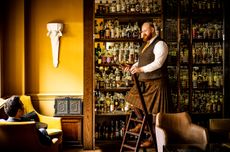 A kilted man fetches a bottle of whisky for a guest at Scotch bar at The Balmoral hotel