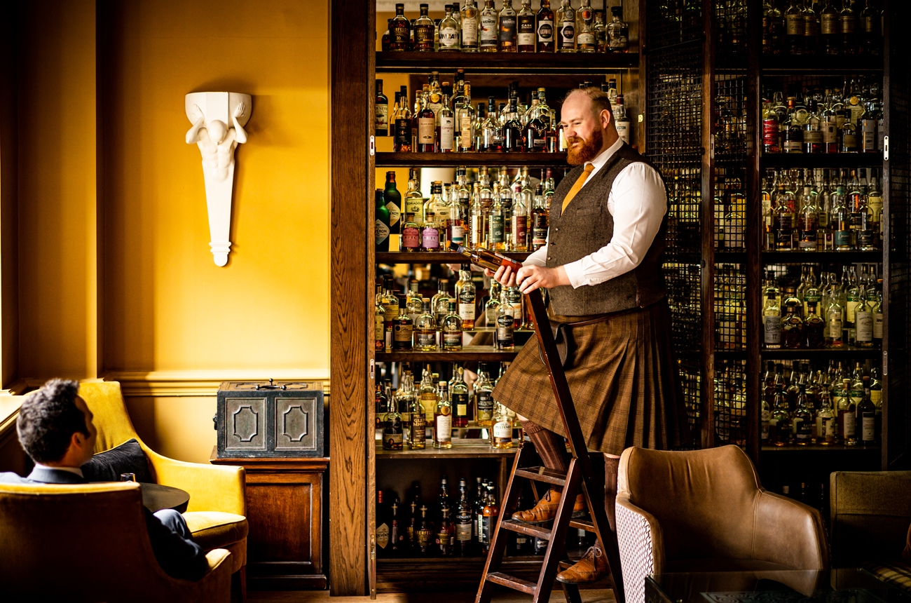 A kilted man fetches a bottle of whisky for a guest at Scotch bar at The Balmoral hotel