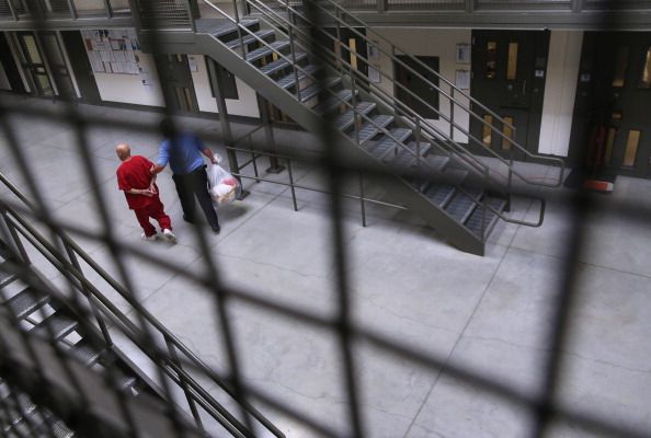 An immigrant detainee is escorted through Adelanto Detention Facility.